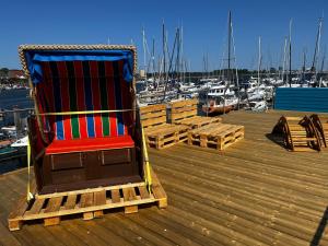 a rocking chair sitting on a dock near a marina at Hausboot Isa - Huus & Meer in Großenbrode-Kai