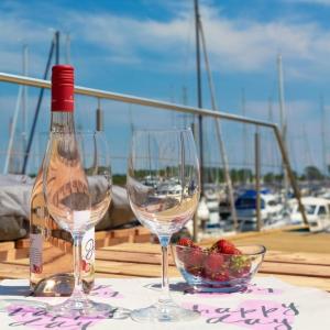 two glasses of wine and a bowl of strawberries on a table at Hausboot Isa - Huus & Meer in Heiligenhafen +18 photos