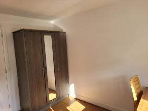 a room with a wooden cabinet and a mirror at Double Room Ensuite in Dartford