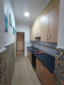 a kitchen with wooden cabinets and a black counter top at Nueva casita de colores in Elche