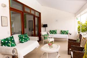 un salon avec des meubles blancs et des coussins verts dans l'établissement Residence Ma Vie Là Ltee, au Morne