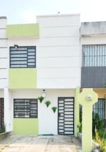 ein weißes und grünes Gebäude mit schwarzen Fenstern in der Unterkunft Casa Comfortable and Complete, maximum 8 people in Tierra Colorada