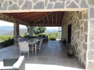 a patio with a table and chairs and a stone building at Maquis et Mer in Sollacaro +2 photos