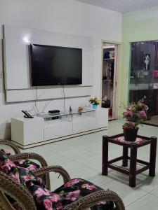 un soggiorno con una TV a schermo piatto su una parete di Casa de praia a Belém