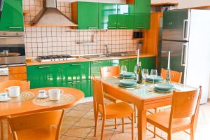 a kitchen with green cabinets and a table with chairs at Casa Azul - Social Apartment - parcheggio, clima, 200mt dal mare in Scoglitti