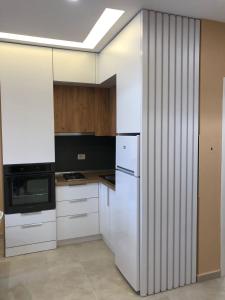a kitchen with white cabinets and a white refrigerator at Fabio Apartment Qerret in Golem +13 photos