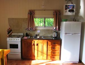 a kitchen with a white refrigerator and a sink at VerdeMonte - Cabaña Guatambú in Leandro N. Alem