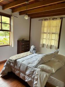 a bedroom with a bed and a window at Chalé Coimbra in São Bento do Sapucaí