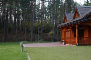 a log cabin with a porch and a grass field at Dzūkų sodžius in Snaigupė +10 photos
