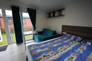 a bedroom with a bed and a chair and windows at Mobilheim Sol in Borgdorf-Seedorf