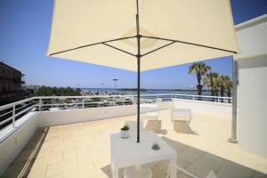 un patio con una mesa blanca y una sombrilla en Riviera Luxury Rooms, en Porto Cesareo