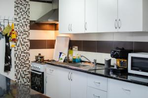 a kitchen with white cabinets and a sink and a microwave at Casa Da Zu in Tomar