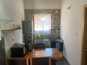 a kitchen with a table and a stove and a window at Mini departamento 2 in Coñaripe
