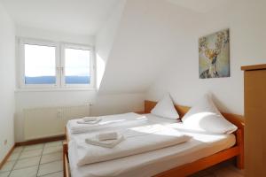 a bedroom with a bed with white sheets and two windows at Ferienwohnung Kraftquelle im Wohnpark SchwarzwaldBlick, Bernau in Bernau im Schwarzwald +17 photos
