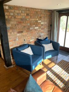 two blue chairs in a room with a brick wall at The Quintessential Dorset Cottage in Lytchett Matravers +43 photos