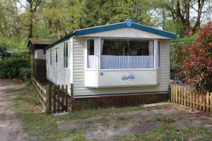 a tiny house with a fence in a yard at Vintage Forest Chalet in IJhorst