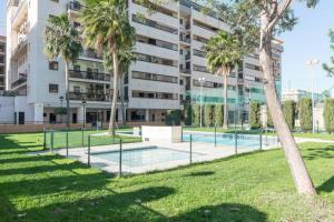 - un court de tennis dans un parc à côté d'un bâtiment dans l'établissement Jardines del Litoral Momas Homes, à Malaga