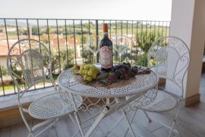 a table with a bottle of wine and grapes on it at Residenza Gli Agrumi del Garda - Bardolino in Bardolino