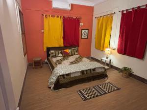 um quarto com 2 camas e cortinas vermelhas e amarelas em Hoglabon nest em kolkata