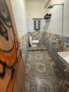 uma casa de banho com WC, lavatório e piso em mosaico em Hoglabon nest em kolkata
