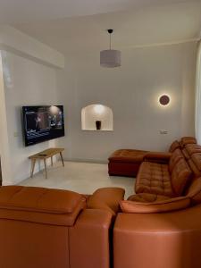 a living room with two leather couches and a flat screen tv at Villa with rooftop hot tub in Tbilisi City