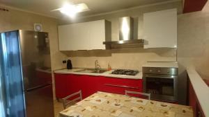 a small kitchen with red cabinets and a table with chairs at La Casetta di Mimma in Viggiano