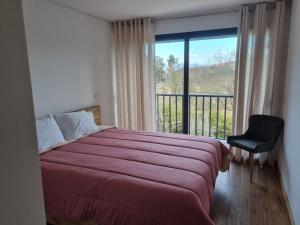 a bedroom with a bed and a window with a balcony at Felicidade in Mondim de Basto +6 photos