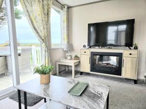 ein Wohnzimmer mit einem TV und einem Kamin in der Unterkunft Cornwall Caravan Retreat, Near Perranporth, 3 Bedroom in Newquay + 51 Fotos