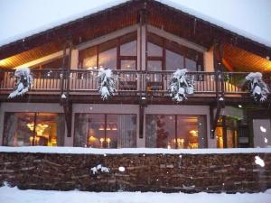Une grande maison avec de la neige sur la terrasse couverte dans l'établissement Hôtel Restaurant La Tourmaline, à Aime La Plagne