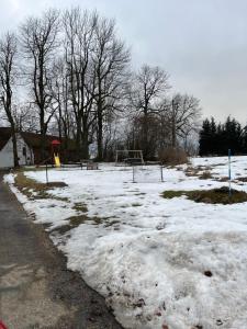 a snow covered park with a playground with a goal at Podkrovní apartmán Studnice in Nové Město na Moravě