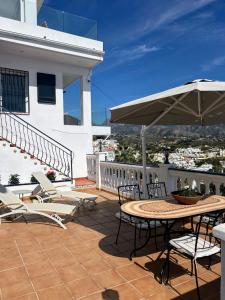 a patio with a table and chairs and an umbrella at Carmen Apartamento Eleanora in Nerja