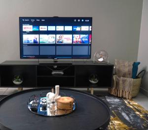 a living room with a table in front of a tv at Two At Urban Pulse in Johannesburg
