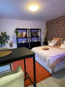 a bedroom with a bed and a table and a brick wall at Nouveau ! Magnifique Studio douillet & Tout confort - Parking - Wifi - Netflix - in Wissembourg
