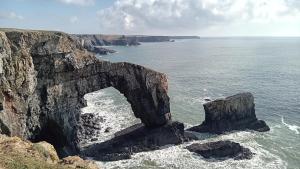 an arch in a rock formation in the ocean at The Owlet at Owl Barn in Flimston
