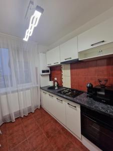 クラヨーヴァにあるBN Titulescu Apartamentの白いキャビネットとコンロ付きオーブンを備えたキッチン