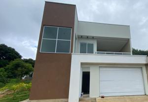 a large white and brown house with a garage at Casa Essenza in Mulungu +6 photos
