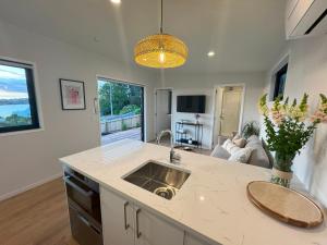 a kitchen with a sink and a living room at Moana Views - Coastal Escape in Whangaparaoa