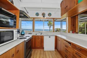 a kitchen with wooden cabinets and a white refrigerator at Hannah's Bay Lakefront in Rotorua