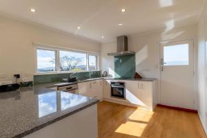 a kitchen with white cabinets and a counter top at All Seasons Escape in Rotorua