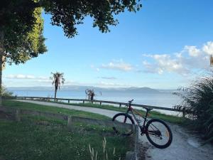 una bicicletta parcheggiata accanto a una recinzione vicino all'oceano di Cozy Lake Retreat Lake Views & Amazing Games Room a Hamurana