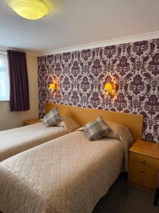two beds in a hotel room with wallpaper at Adelaide House Hotel - Opposite Winter Gardens, Town Centre in Blackpool
