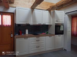 a kitchen with white cabinets and a stove top oven at Kellerstöckl am Sauerberg 27 in Moschendorf