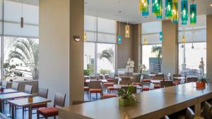 a restaurant with tables and chairs and windows at Hyatt Place Managua in Managua