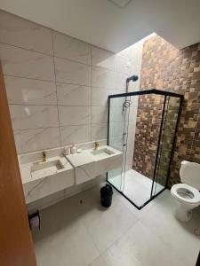 Un baño con ducha, lavabo e inodoro. en Casa guaratuba com piscina esquerdo, en Guaratuba