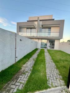 un gran edificio con un patio de césped delante de él en Casa guaratuba com piscina esquerdo, en Guaratuba
