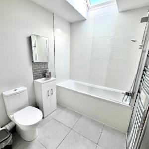 a white bathroom with a toilet and a bath tub at Apple Lodge - Somerset Holiday Homes in North Wootton