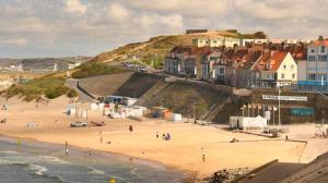 a beach with a bunch of buildings on a hill at Au bruit des vagues in Le Portel