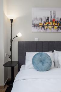 a blue pillow on a white bed with a lamp at Ladadika Urban Apartment Two Bedroom in Thessaloniki