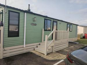 a green and white house with a porch and stairs at Green House Moselle in Jaywick Sands