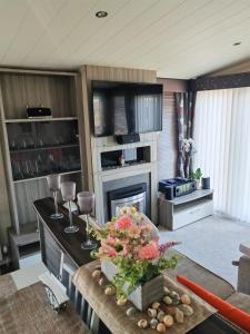 a living room with a fireplace and a table with wine glasses at Green House Moselle in Jaywick Sands +10 photos